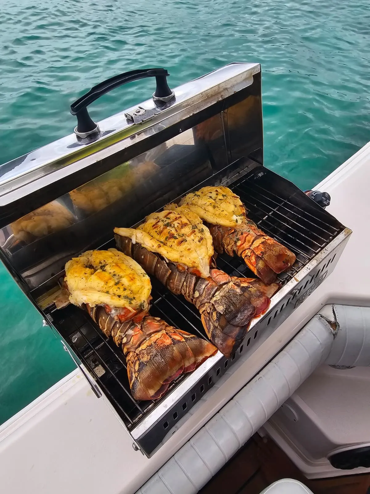 Caribbean lobster tails grilling in butter on the boat's onboard BBQ