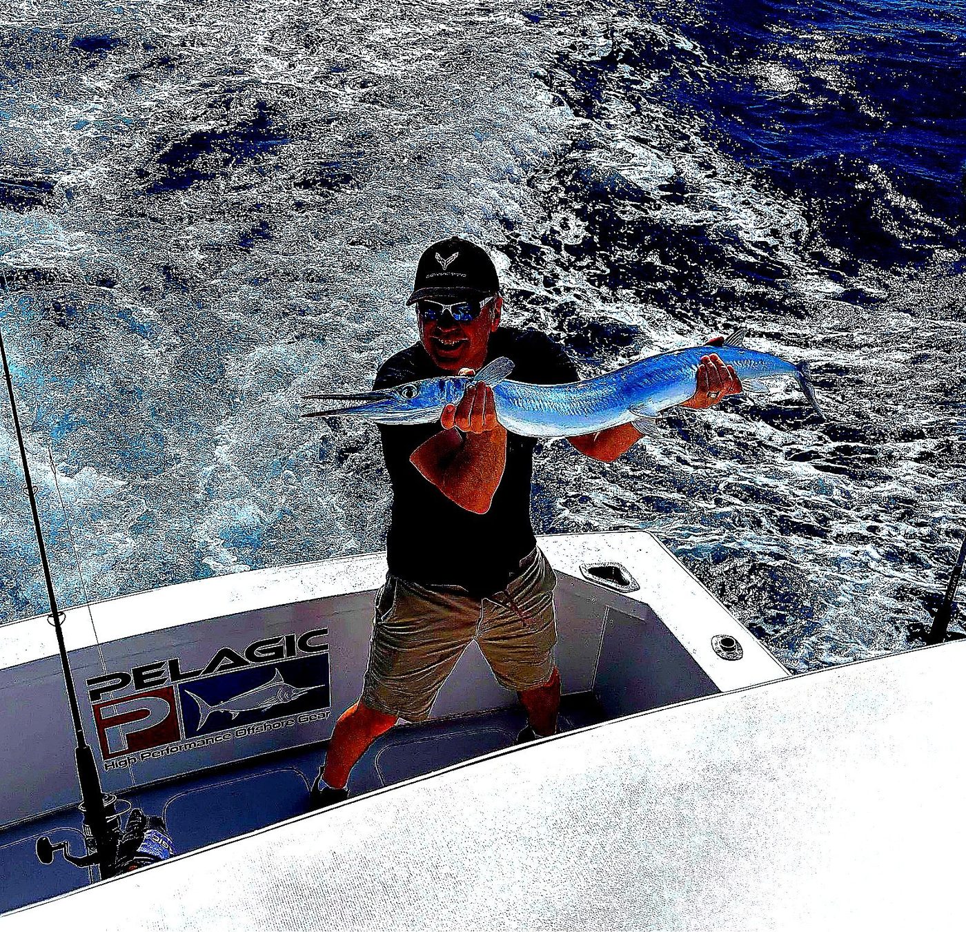 Angler holding a fish offshore with ocean wake behind