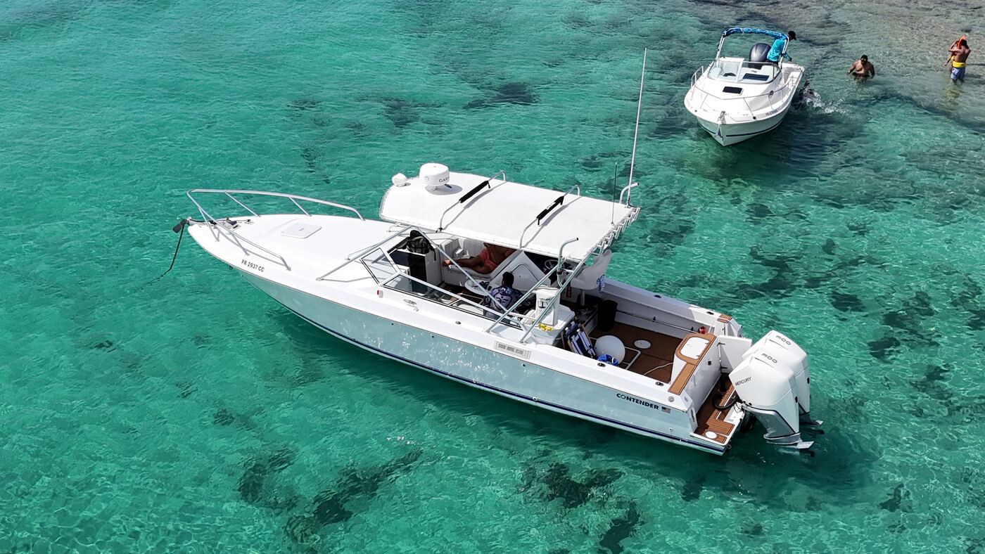 Contender 38ft charter boat anchored in turquoise water off Fajardo Puerto Rico, teak deck and twin Mercury outboards visible