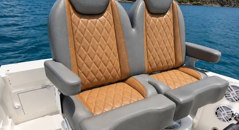 Twin helm seats on the Hydra Sport 25 upholstered in tan diamond-stitched vinyl, with the green coastline of Fajardo, Puerto Rico behind
