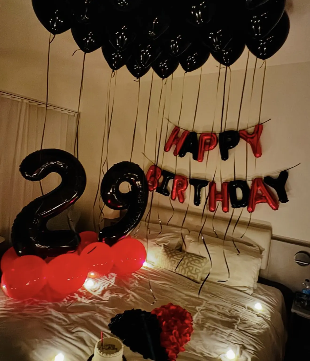 Black and red balloon birthday setup with number balloons and cake
