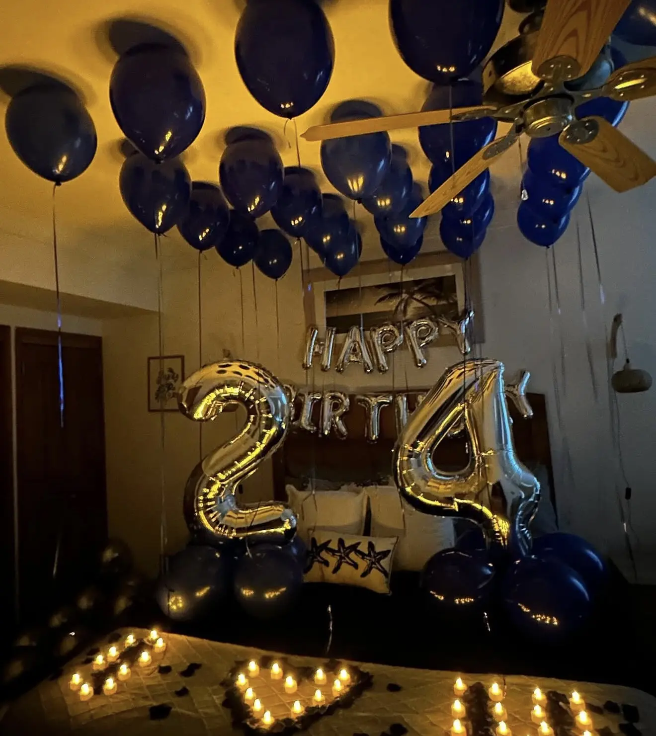 Navy and gold balloon birthday setup with candlelit heart
