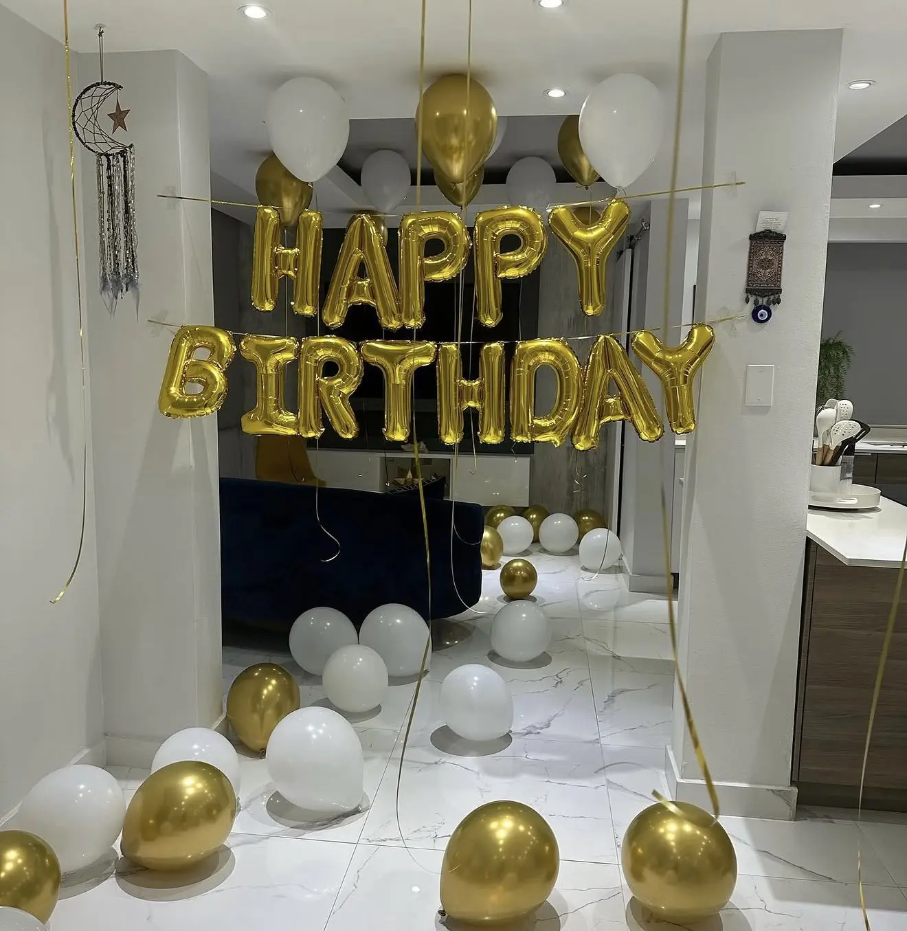 Gold and white balloon birthday setup with Happy Birthday sign