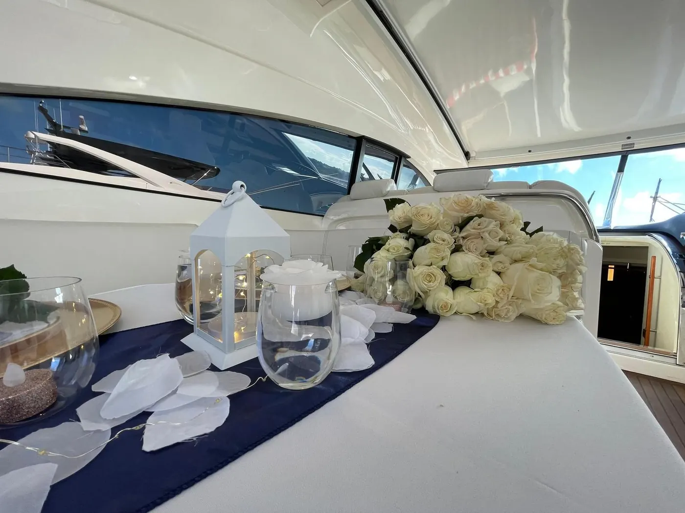 Romantic proposal setup with white roses lanterns and petals onboard yacht