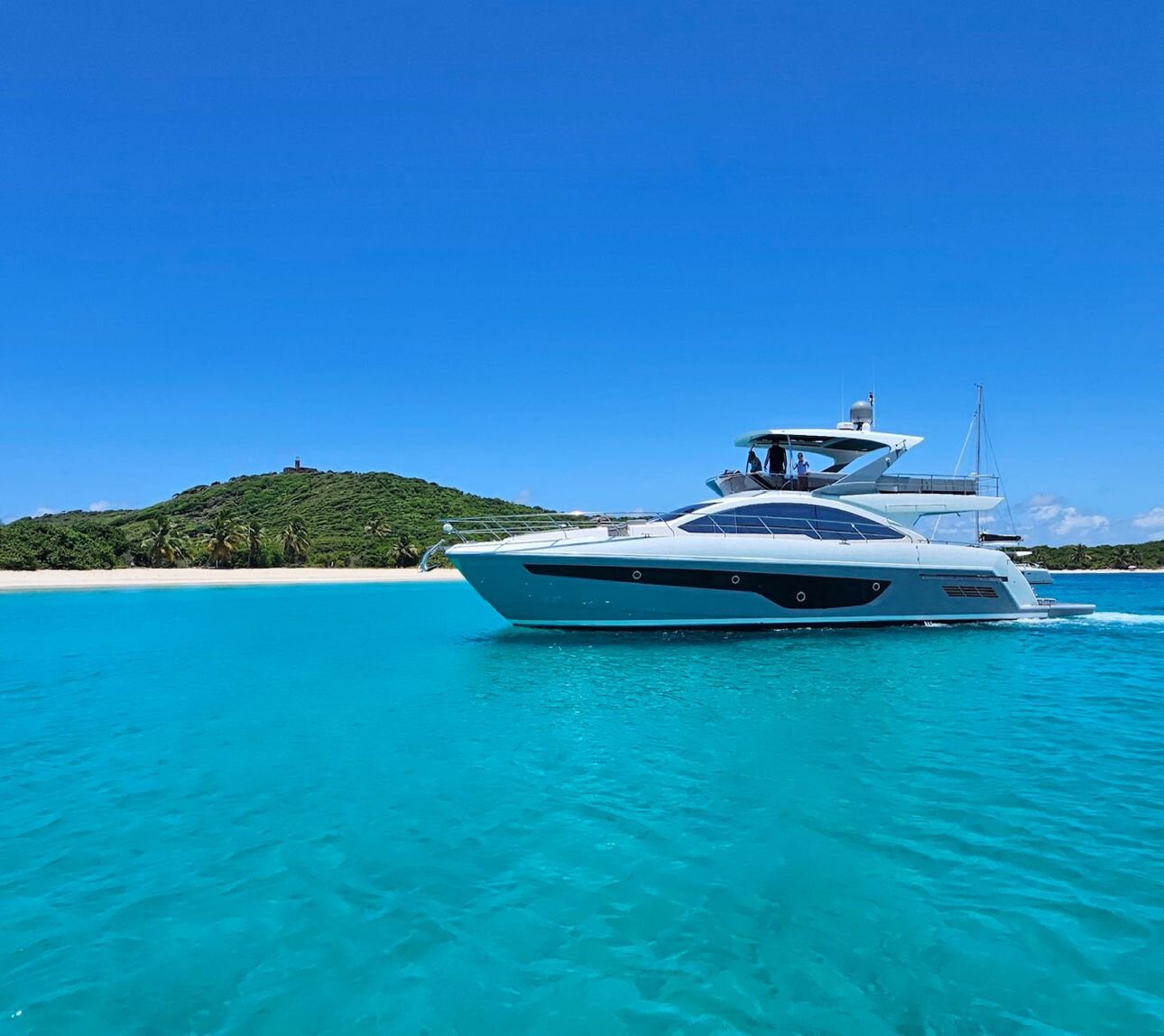 Luxury motor yacht anchored next to Culebrita island lighthouse — private yacht charters in Puerto Rico