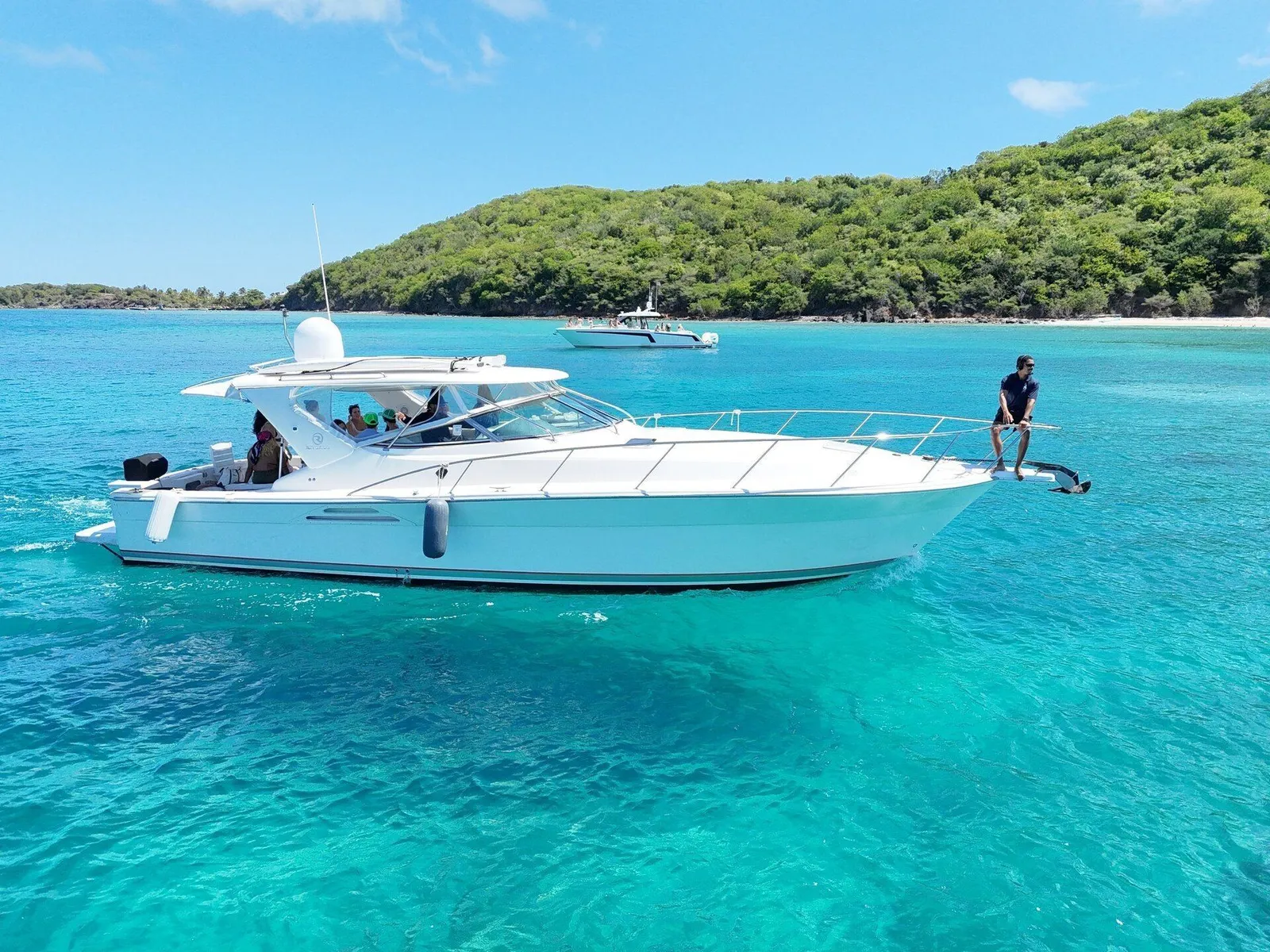 Sport yacht anchored at Caribbean sandbar with guest on the swim platform, turquoise water