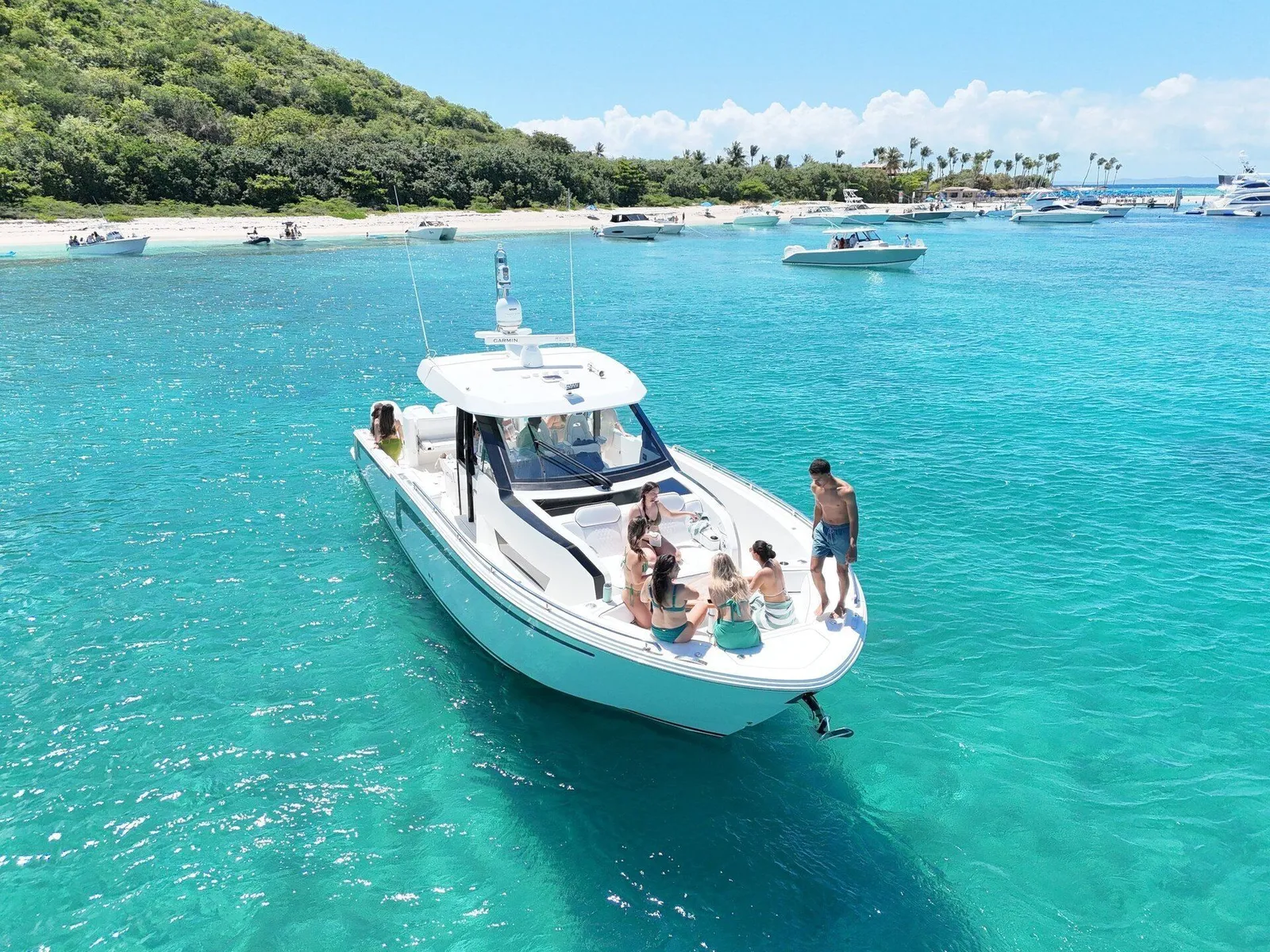 Aerial drone view of charter yacht with guests celebrating on the bow at a Caribbean sandbar in Puerto Rico