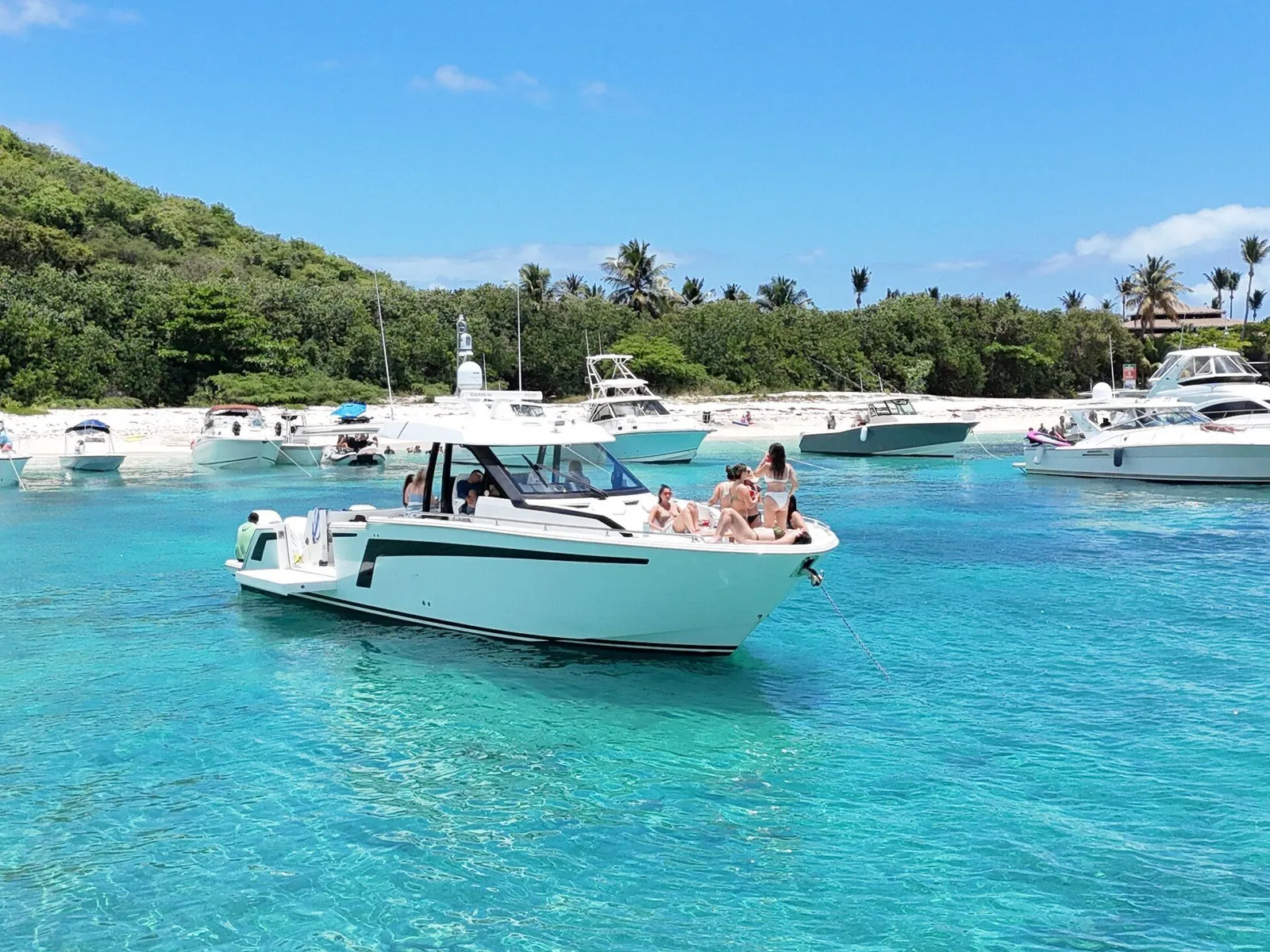 Group of guests on the bow of an Axopar charter at Icacos sandbar with green tropical hill