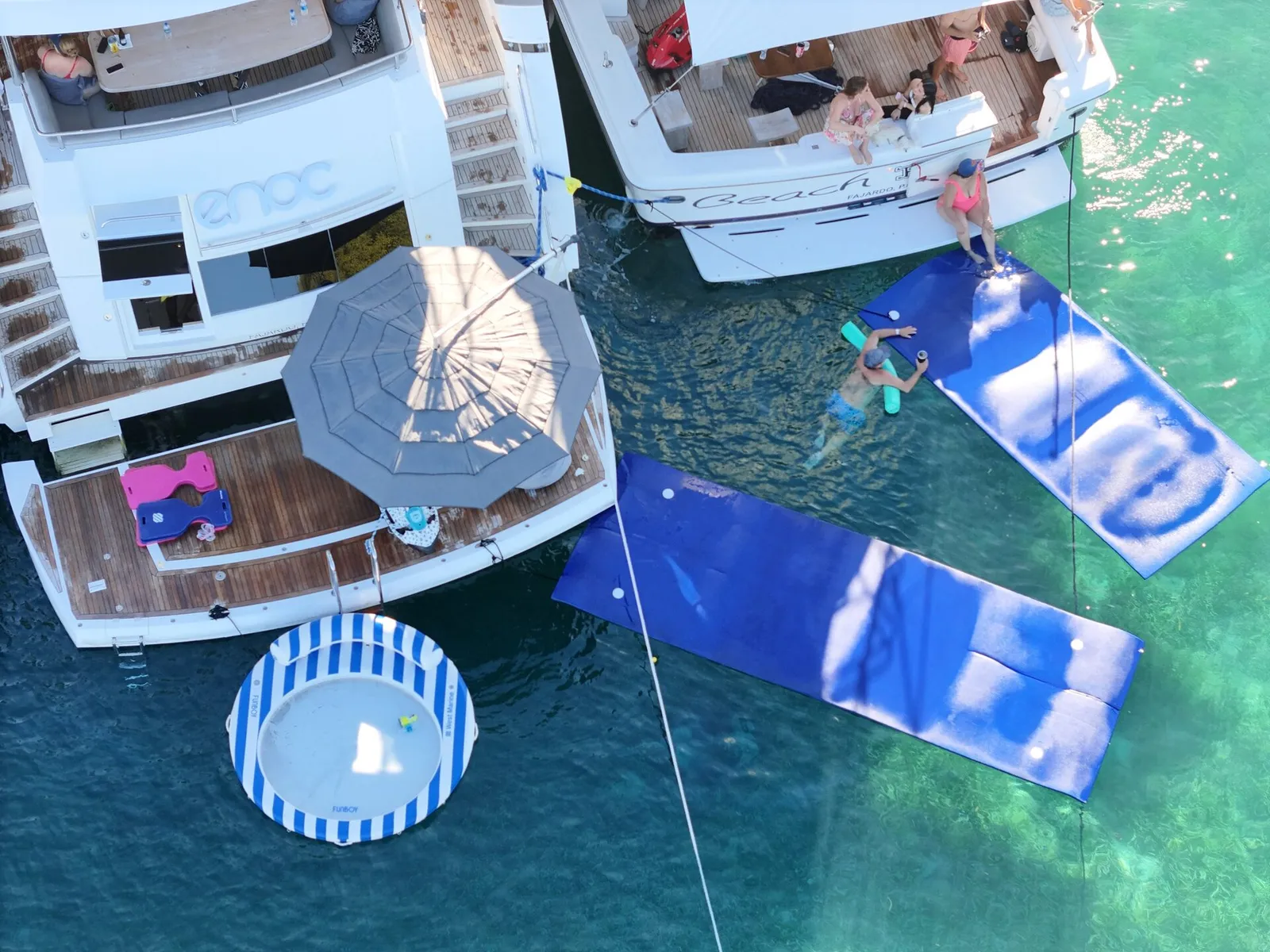 Top-down aerial of two luxury yachts side-by-side with floating mats at the Caribbean sandbar