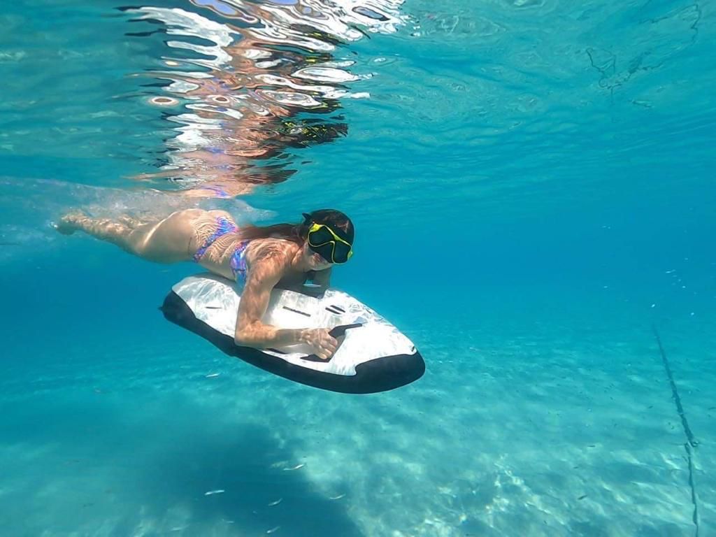 Rider gliding underwater on a Seabob beside a yacht in crystal clear Caribbean water